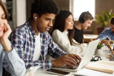 A group of people sitting at tables with laptops.