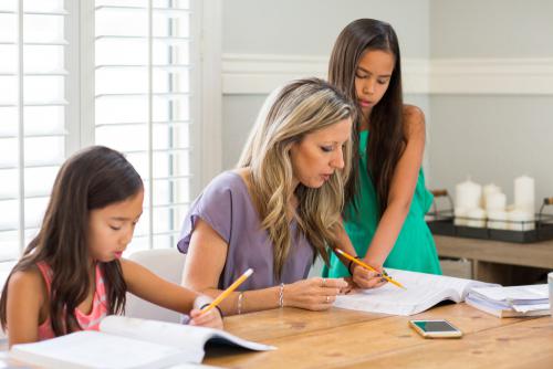 A group of women sitting at a table writing on paper.