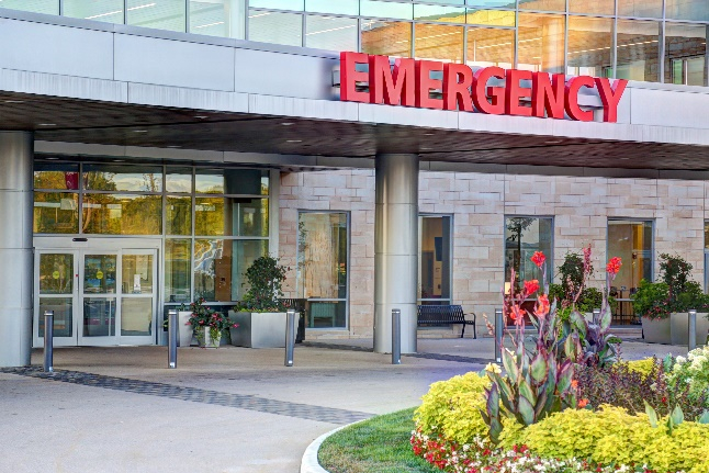 A hospital entrance with flowers in front of it.