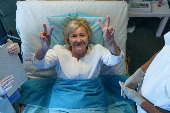 A woman laying in bed with her hands up.