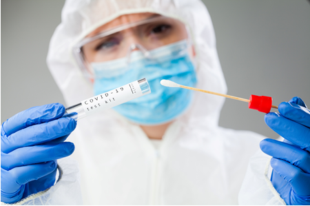 A person in white lab coat holding up two syringes.