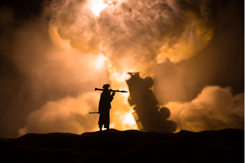 A person holding two bats in front of smoke.