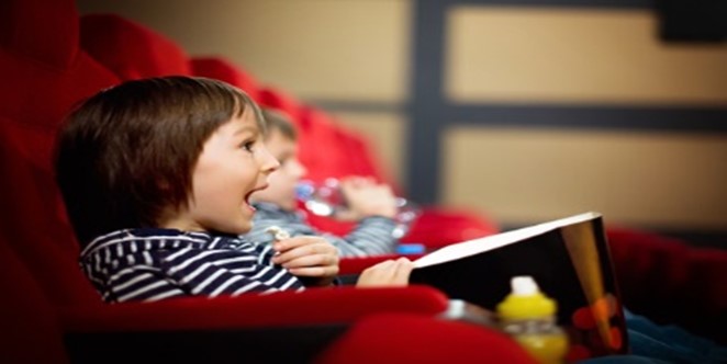 Two children sitting in a red chair and laughing.