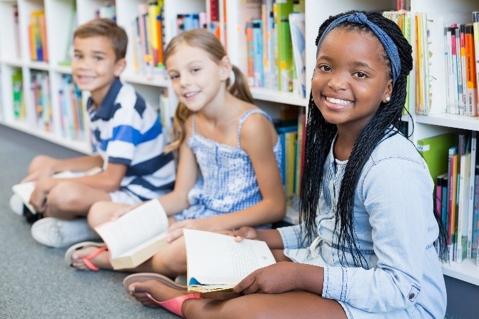 A group of children sitting in front of books.