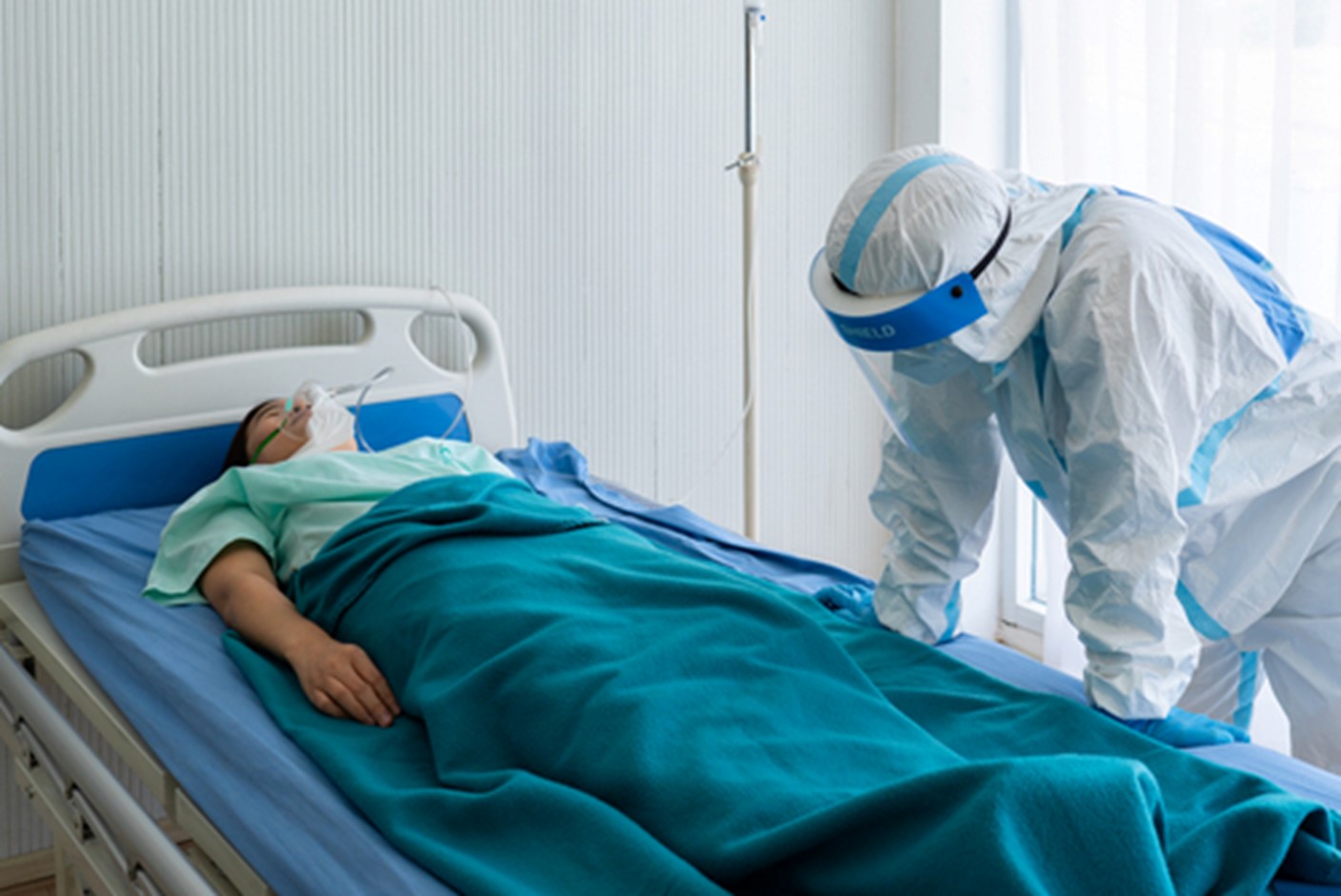 A person in a hospital bed with a nurse looking on.