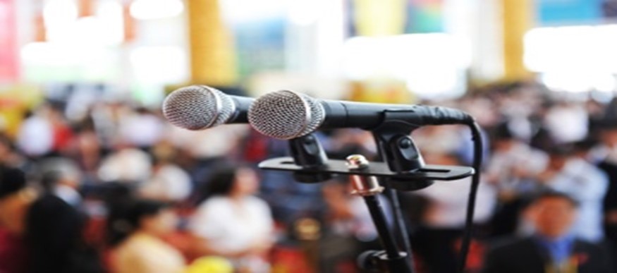 Two microphones are on a stand in front of people.