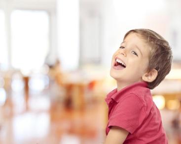 A young boy smiling and sitting on the floor.