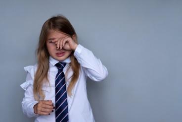 A girl in white shirt and tie holding her hand to the side.