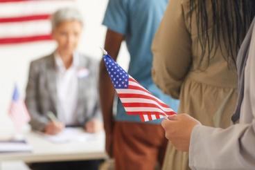 A person holding an american flag in front of other people.