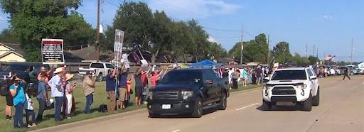 A black truck driving down the street near people.