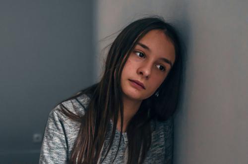 A young girl leaning against the wall with her head on one side.