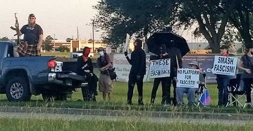 A group of people standing under an umbrella.