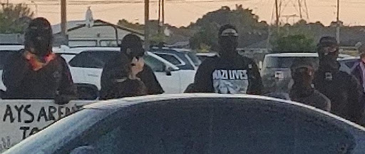 Two men in black masks are sitting in a car.