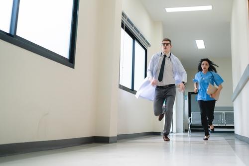 A man and woman running in an office hallway.