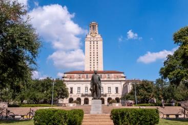 A statue of a man in front of the ut tower.