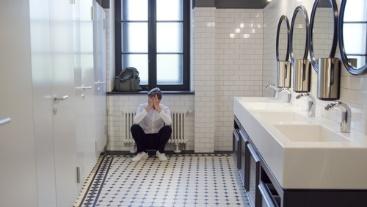 A man sitting on the floor of his bathroom