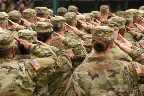 A group of soldiers saluting in front of an audience.