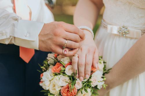 A man and woman holding hands with wedding rings on their fingers.