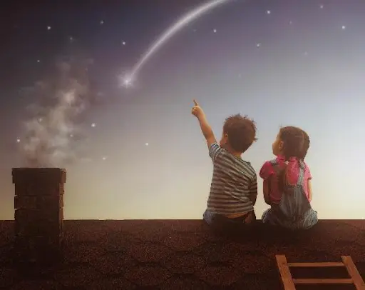 Two children sitting on a roof looking at the sky