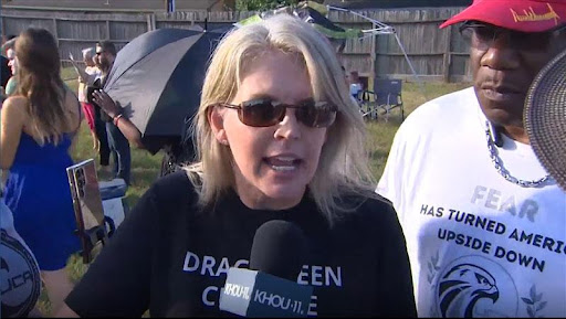 A woman in sunglasses and a black shirt is talking to the camera.