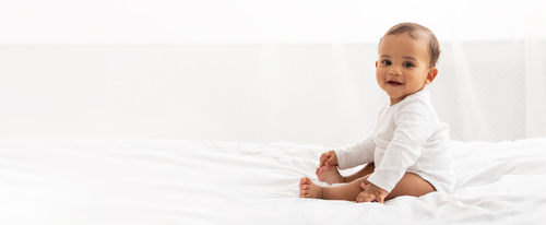 A baby sitting on top of a bed.