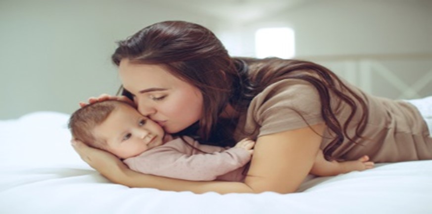 A woman kissing her baby on the cheek.