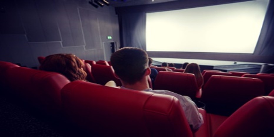 A man and woman watching a movie in the theater.