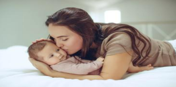 A woman kissing her baby on the cheek.