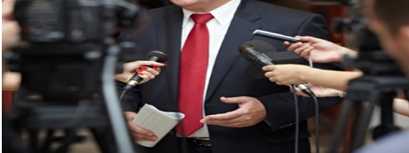 A man in a suit and tie holding microphones.