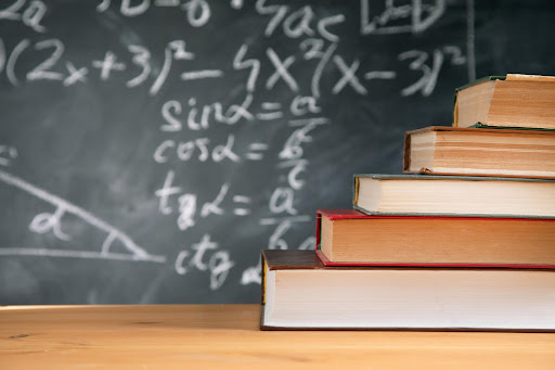 A stack of books on top of each other in front of a chalkboard.