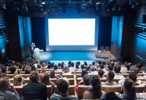 A group of people sitting in front of a projector screen.