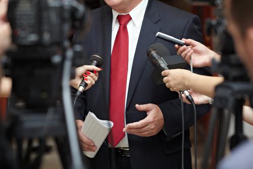 A man in a suit and tie holding microphones.