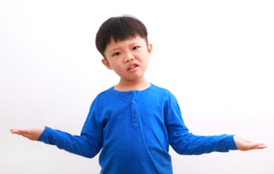 A young boy in blue shirt standing with arms outstretched.