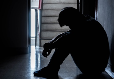 A person sitting on the floor in front of stairs.