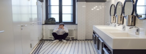 A man sitting on the floor of a bathroom.