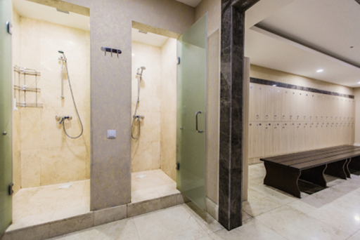 A bathroom with two walk in shower stalls and a bench.