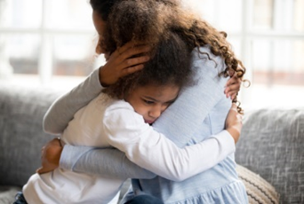 A woman and child hug each other in the living room.