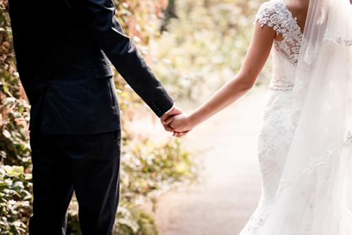 A man and woman holding hands while walking down the street.