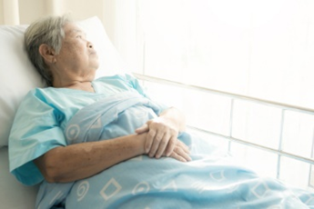 A woman laying in bed with her hands folded over her chest.