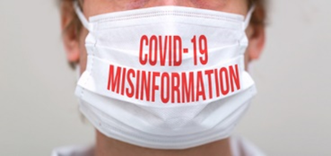 A person wearing a face mask with the words covid-1 9 misinformation written on it.