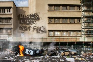 A fire burning in the street next to a building.