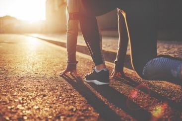 A person is tying their shoes on the street.