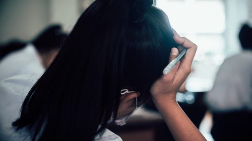 A woman with long black hair is holding her phone.