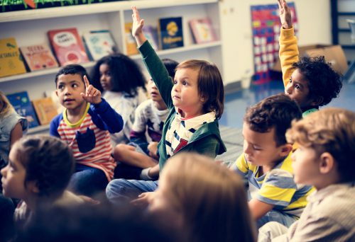 A group of children sitting in front of books.